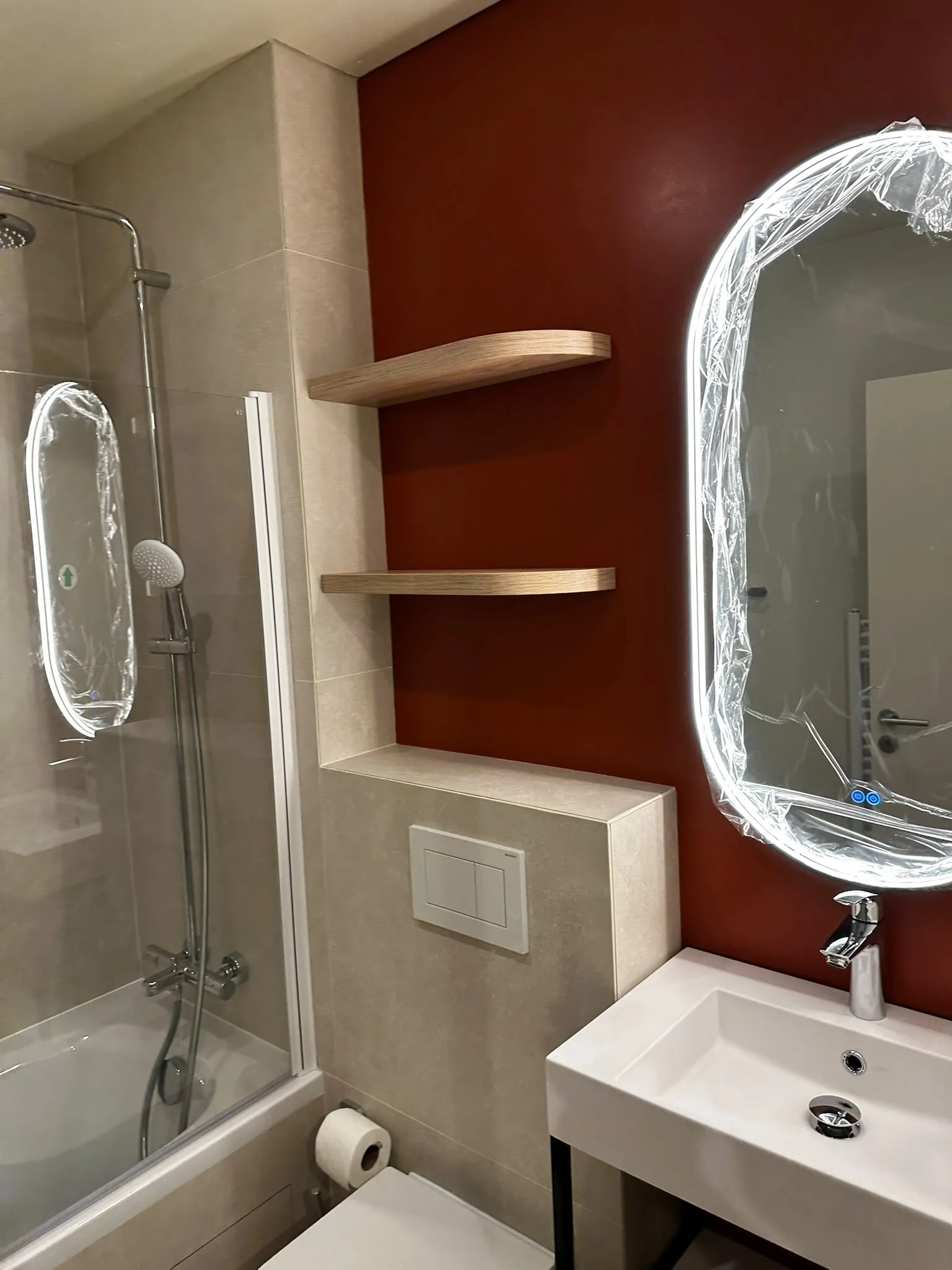 Terracotta wall, shelving and illuminated bathroom mirror