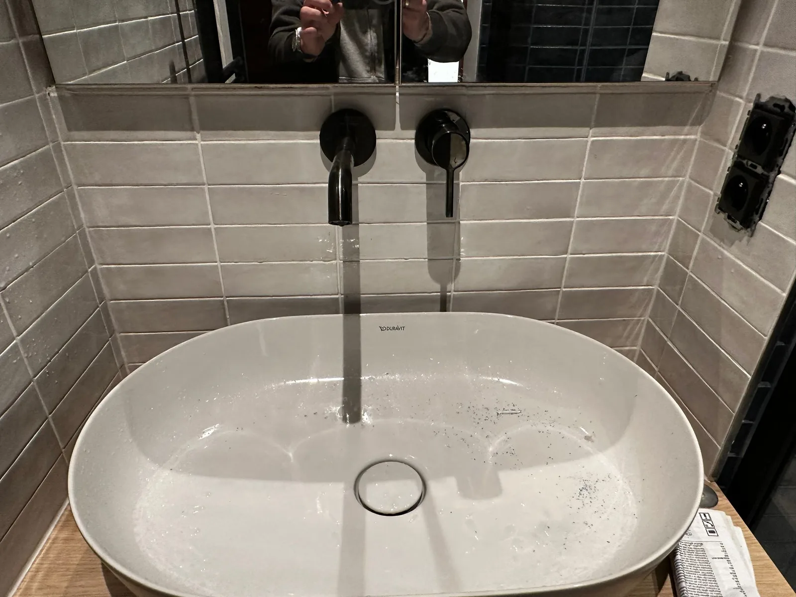 White basin and black wall-mounted taps