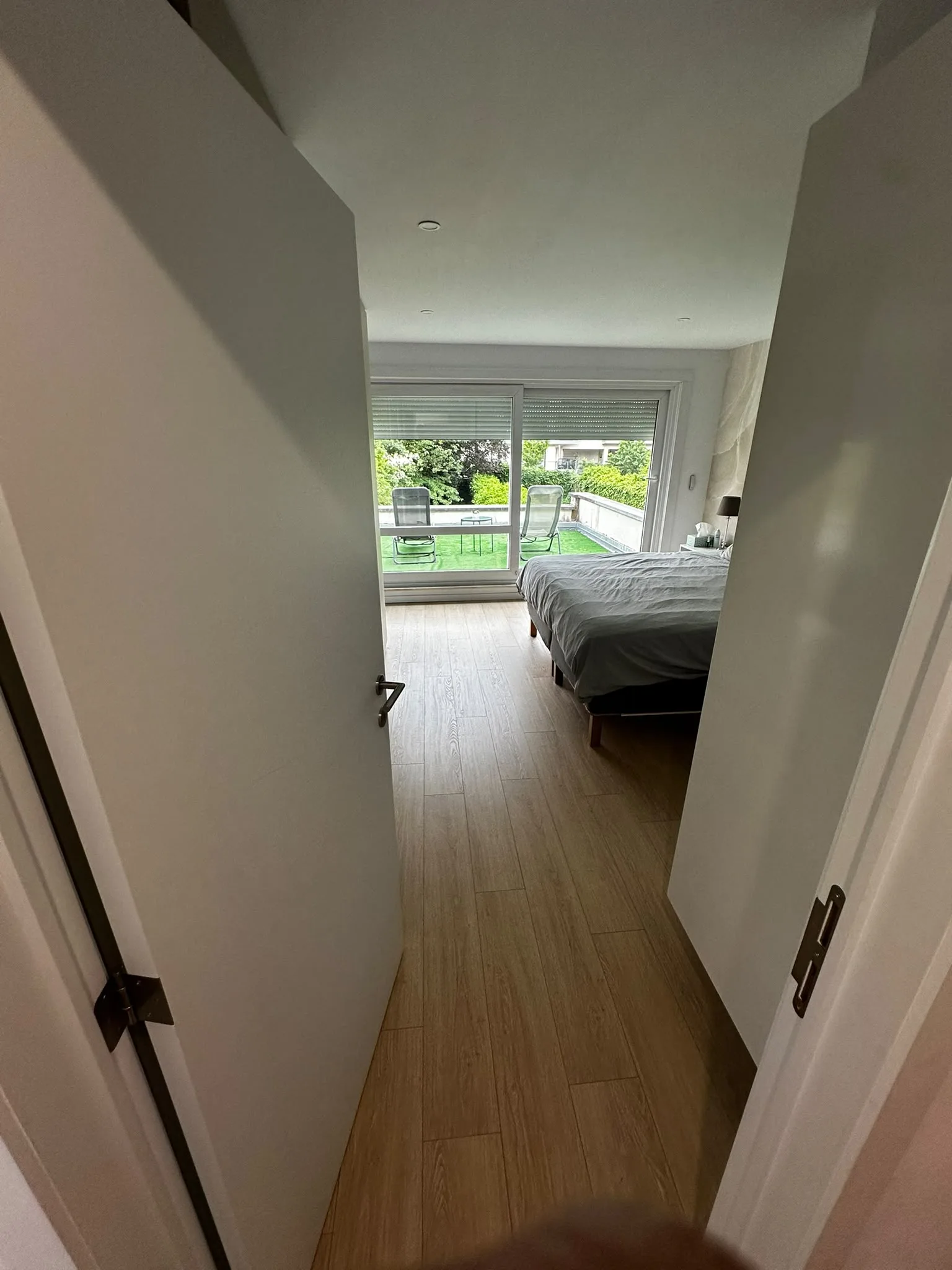 Chambre avec sol aspect bois et accès à la terrasse