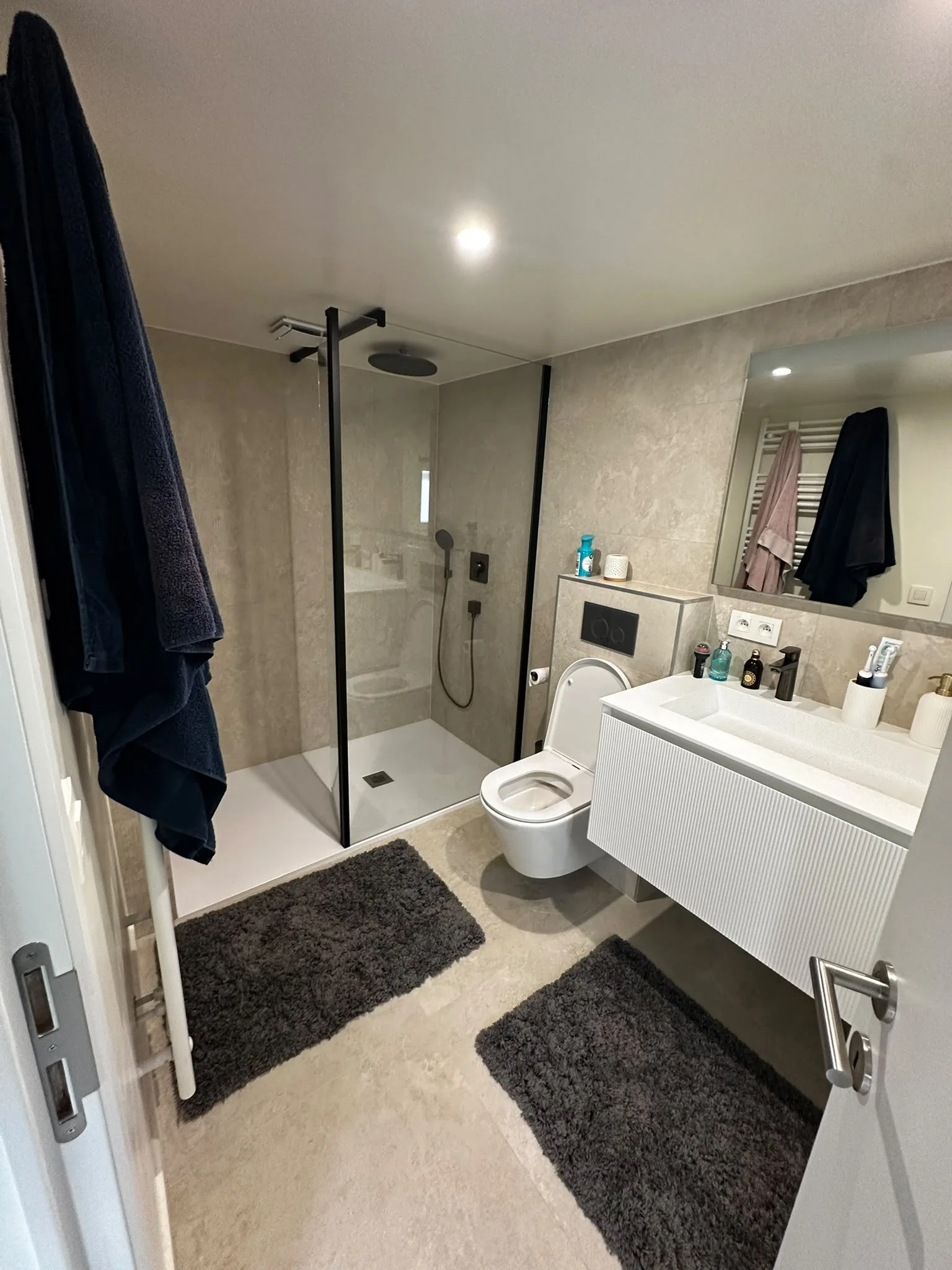 Salle de bain avec douche vitrée, WC suspendu et meuble blanc