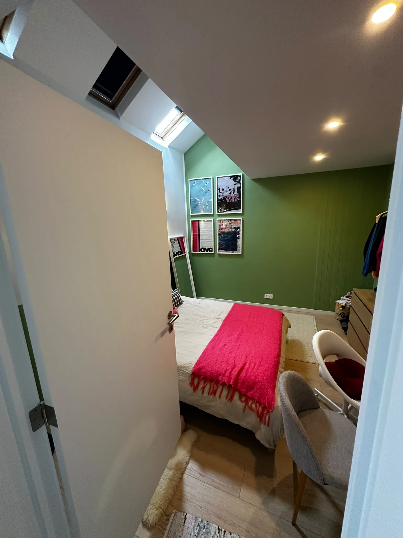 Chambre sous toiture avec fenêtres de toit et mur vert