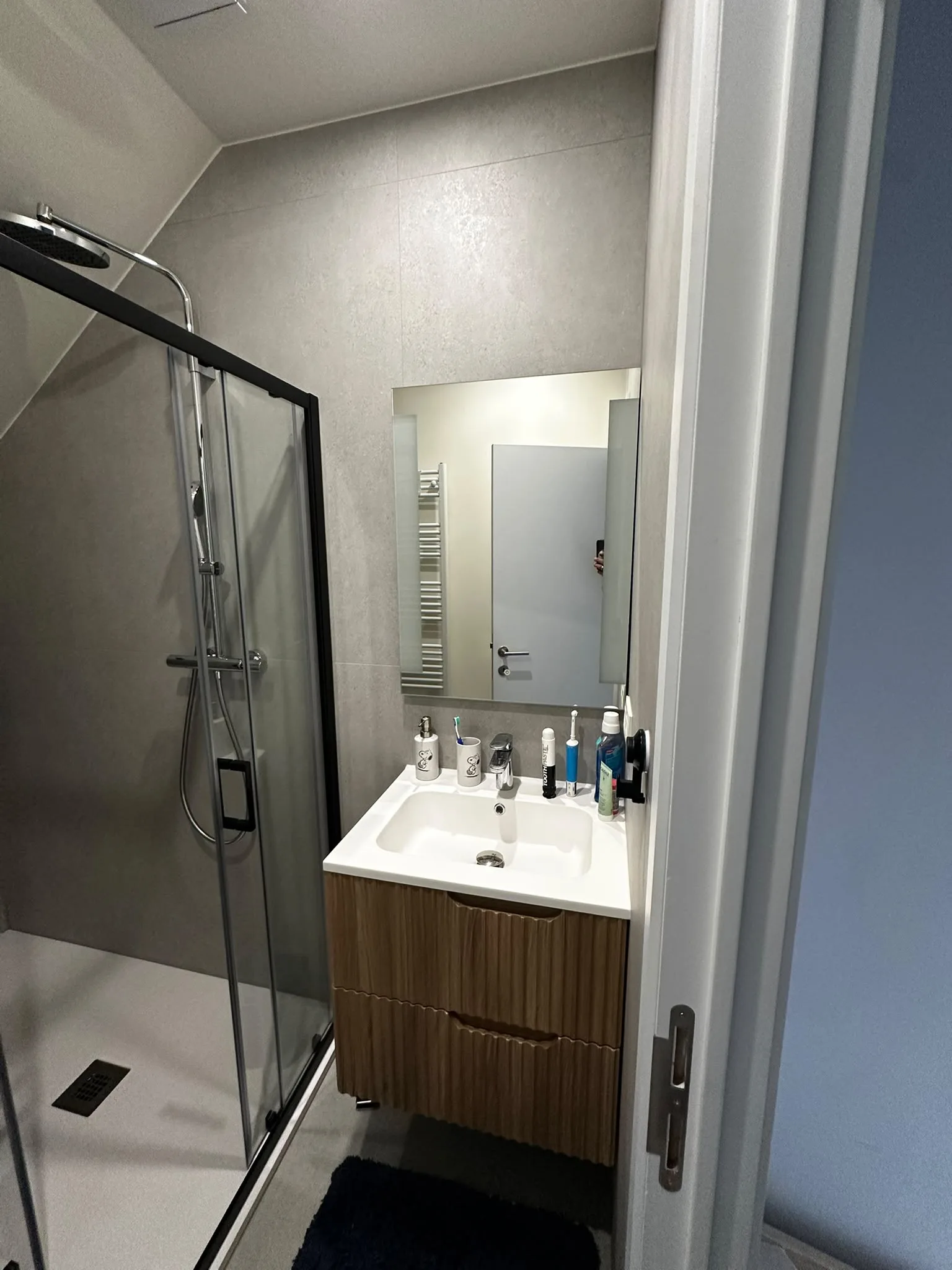 Meuble compact aspect bois, miroir et douche encadrée de noir