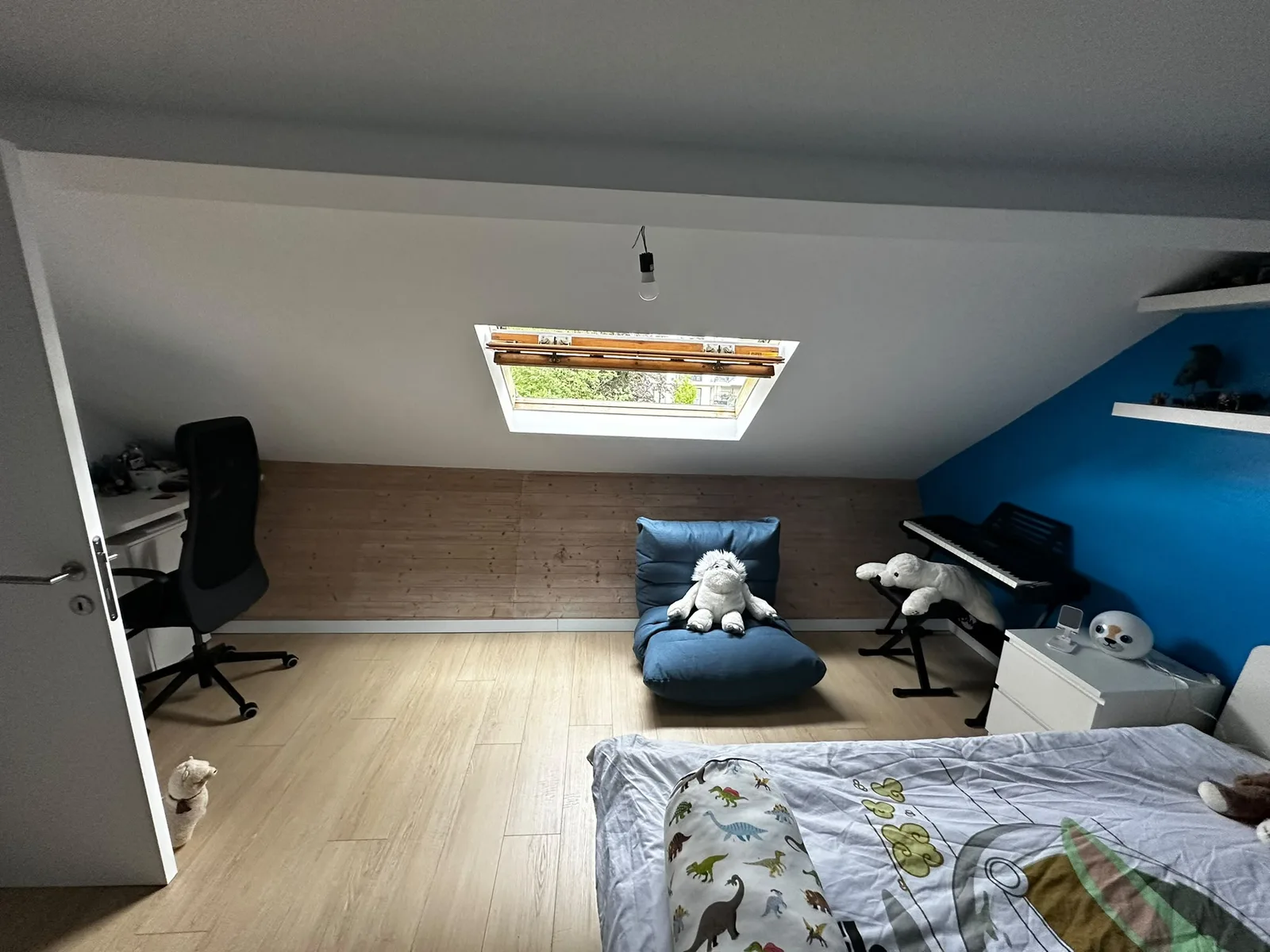 Chambre mansardée avec fenêtre de toit et soubassement en bois