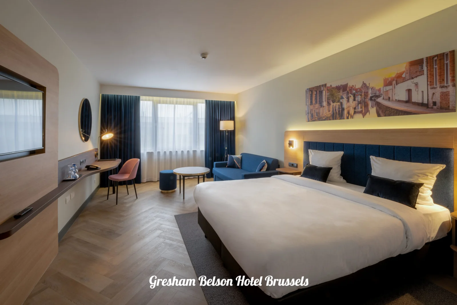Kamer met tweepersoonsbed, blauw hoofdbord en zithoek